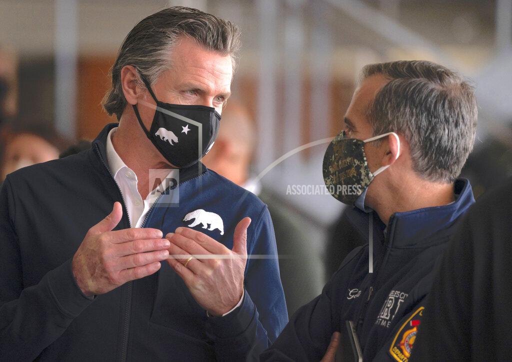Jae C. Hong FILE _ In this Feb. 16, 2021 file photo, California Gov. Gavin Newsom, left, talks to Los Angeles Mayor Eric Garcetti during a news conference at a joint state and federal COVID-19 vaccination site set up on the campus of California State University of Los Angeles in Los Angeles. Students in California classrooms can sit 3 feet apart instead of 6 under new guidelines adopted by the state as school officials figure out how to reopen campuses closed for a year during the coronavirus pandemic. (AP Photo/Jae C. Hong, File)