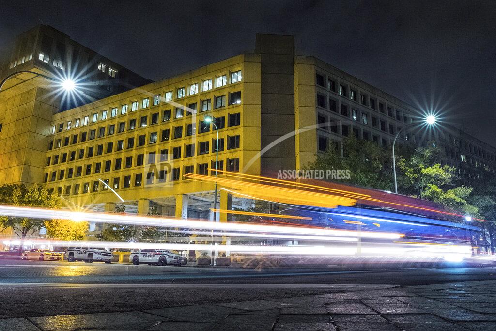 FILE - In this Nov. 1, 2017, file photo, traffic along Pennsylvania Avenue in Washington streaks past the Federal Bureau of Investigation headquarters building. In an alert Wednesday, Oct. 28, 2020, the FBI and other federal agencies warned that cybercriminals are unleashing a wave of data-scrambling extortion attempts against the U.S. healthcare system that could lock up their information systems just as nationwide cases of COVID-19 are spiking. (AP Photo/J. David Ake, File)