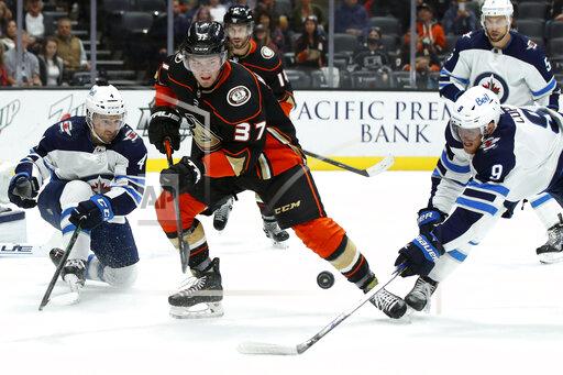 Anaheim Ducks center Mason McTavish (37) and Winnipeg Jets center Andrew Copp (9) work for the puck with defenseman Neal Pionk (4) watching during the second period of an NHL hockey game in Anaheim, Calif., Wednesday, Oct. 13, 2021. (AP Photo/Alex Gallardo)