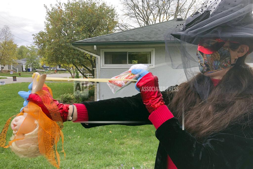 Julie Carr Smyth Julie Schirmer demonstrates the slingshot she’ll use to deliver Halloween candy from afar at her home in Columbus, Ohio, on Saturday, Oct. 24, 2020. The favorite American festivity of Halloween trick-or-treating is being tested by the pandemic, and people are rising to the challenge in creative ways that are both safe and fun. (AP Photo/Julie Carr Smyth)