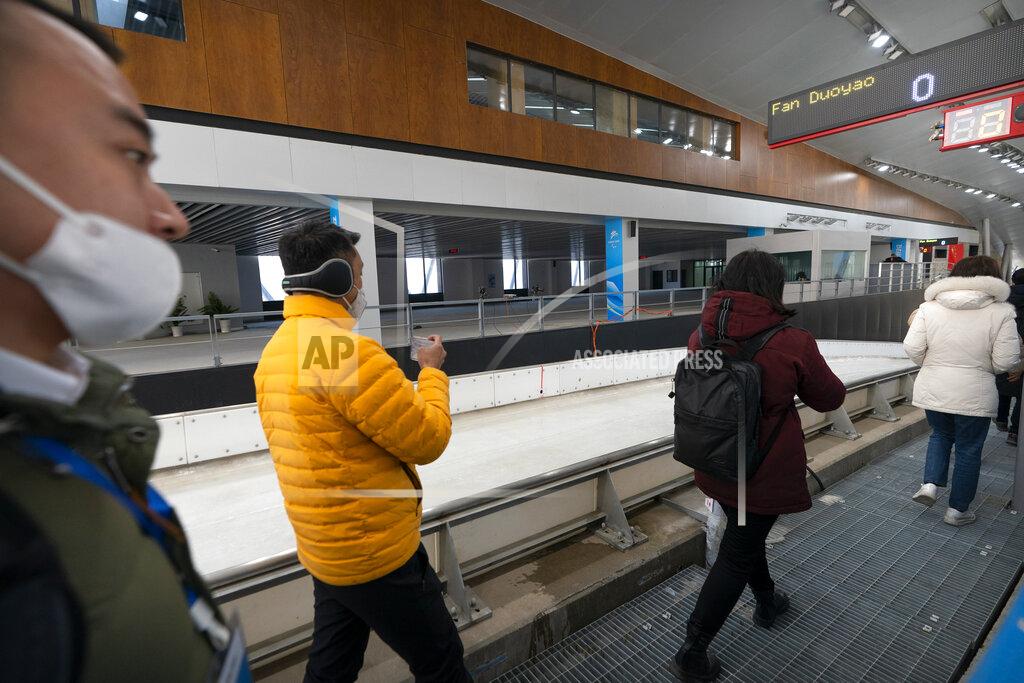 Mark Schiefelbein Journalists wearing face masks to protect against the spread of the coronavirus walk along the ice run at the National Sledding Center in Yanqing on the outskirts of Beijing, Friday, Feb. 5, 2021. Beijing Olympic organizers showed off the downhill skiing venue and the world's longest bobsled and luge track Friday, one year ahead of the scheduled opening of the 2022 Olympic Winter Games. (AP Photo/Mark Schiefelbein)
