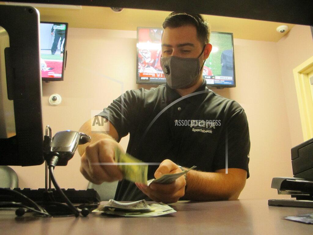 Wayne Parry A clerk counts money at the sports betting lounge at Freehold Raceway in Freehold, N.J. on Oct. 24, 2020. A report released Feb. 2, 2021 by the American Gaming Association predicts fewer Americans will bet on this year's Super Bowl, a decrease driven largely by fewer people back at work in offices where betting pools are circulated. But the report also predicts a record amount will be wagered online this year. (AP Photo/Wayne Parry)