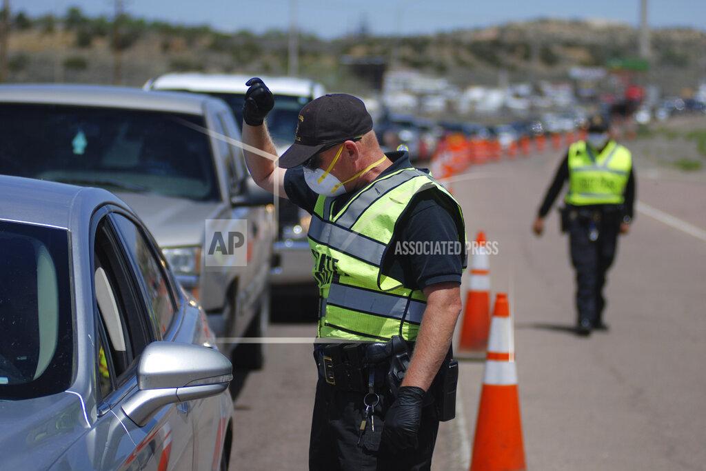 Morgan Lee FILE - In this May 7, 2020, file photo, New Mexico state police officers screen cars for compliance with an emergency lockdown order that bans nonessential visitors and limits vehicle passengers to two people as they enter Gallup, N.M. New Mexico Sheriffs' Association President Tony Mace and State Republican Party Chairman Steve Pearce each sent letters to U.S. Attorney General William Barr last week seeking a review into the health orders that have shuttered some businesses since late March. They allege the order, which has closed several small businesses, violates residents' civil rights. (AP Photo/Morgan Lee, File)