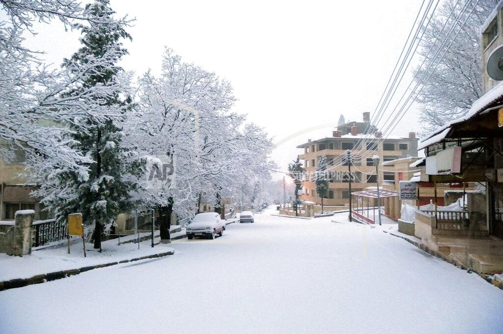 Uncredited In this photo released by the Syrian official news agency SANA, snow covers a street in the town of Slanfah, in Latakia province, Syria, Wednesday, Feb. 17, 2021. Snow blanketed parts of Syria, Lebanon, Jordan and Israel on Wednesday, blocking roads, disrupting traffic and postponing vaccination campaigns against COVID-19 and even exams at some universities. (SANA via AP)