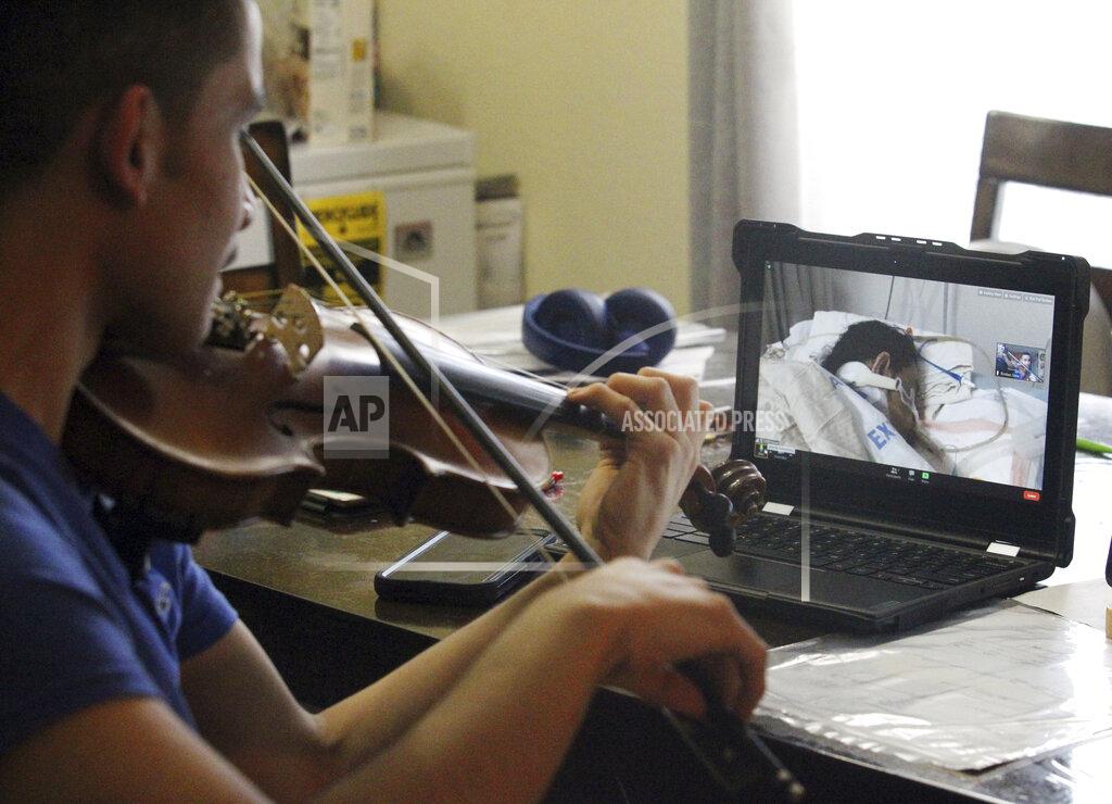 Delcia Lopez FILE - In this Wednesday, Jan. 27, 2021 file photo, Emilian Sosa, 14, plays the violin for his mother seen on a computer screen at her hospital bed in McAllen, Texas. Sosa says his mother Erika Calderon has been battling COVID-19 for more than 20 days and needs Extracorporeal Membrane Oxygenation (ECMO) therapy to help her recover. (Delcia Lopez/The Monitor via AP, File)