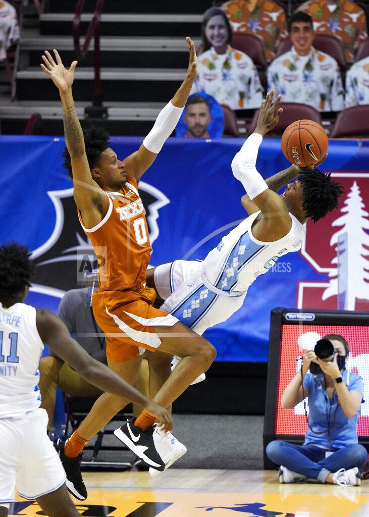 Kathy Kmonicek North Carolina guard Caleb Love (2) falls backwards as his shot at the basket is blocked by Texas forward Gerald Liddell (0) in the first half of an NCAA college basketball game for the championship of the Maui Invitational, Wednesday, Dec. 2, 2020, in Asheville, N.C. Texas won 69-67. (AP Photo/Kathy Kmonicek)
