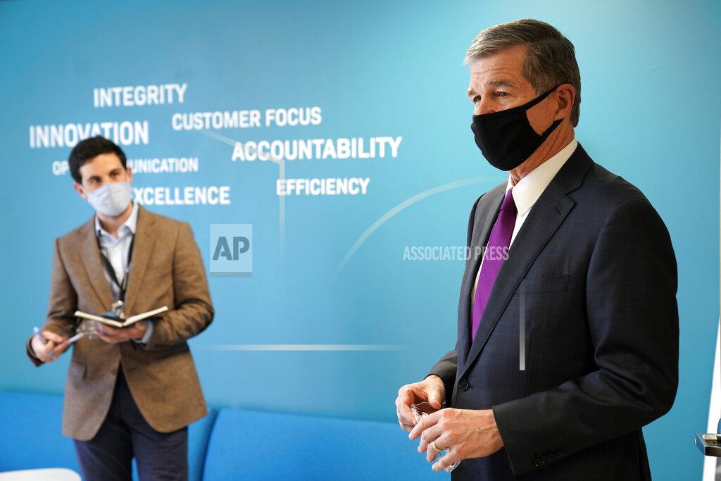 Gov. Roy Cooper, right, is seen during a visit to Gilero in Pittsboro, N.C., Thursday, Dec. 3, 2020. The medical device manufacturer began producing face shields when the pandemic started and also produces swabs for rapid tests in addition to self contained oxygenated negative pressure environments. (AP Photo/Gerry Broome)