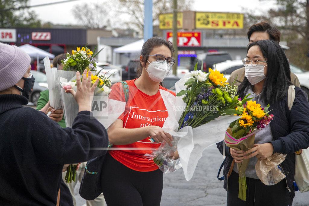 Alyssa Pointer FILE - In this March 17, 2021, file photo, Roula AbiSamra, center, and Chelsey, right, prepare to lay flowers bouquets at a makeshift memorial outside of the Gold Spa in Atlanta. Asian Americans were already worn down by a year of pandemic-fueled racist attacks when a white gunman was charged with attacking three Atlanta-area massage parlors and killing eight people, most of them Asian women. (Alyssa Pointer/Atlanta Journal-Constitution via AP, File)