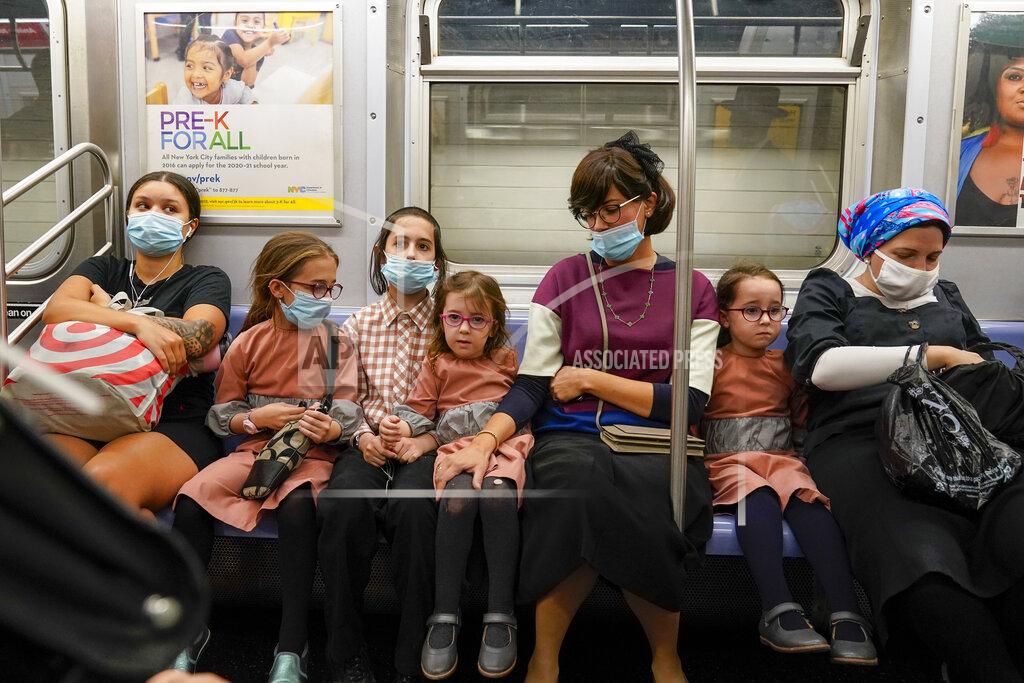 Mary Altaffer A family, some wearing face masks and some not, ride the subway, Monday, Sept. 14, 2020, in the Brooklyn borough of New York. The Metropolitan Transportation Authority announced a new public service campaign to encourage mask usage as well as a new $50 fine policy for those who refuse to wear face coverings on subways, buses and commuter railroads. (AP Photo/Mary Altaffer)