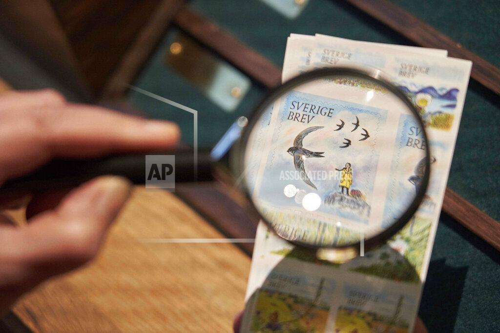 David Keyton Swedish teenage environmental activist Greta Thunberg appears on a postal stamp in her native Sweden that is part of a series focusing on the environment, as seen through a magnifying glass, in Stockholm, Wednesday, Jan. 13, 2021. One of the stamps features teenage environmental activist Greta Thunberg in her trademark yellow raincoat with her braid blowing in the wind and standing a top a hill. (AP Photo/David Keyton)
