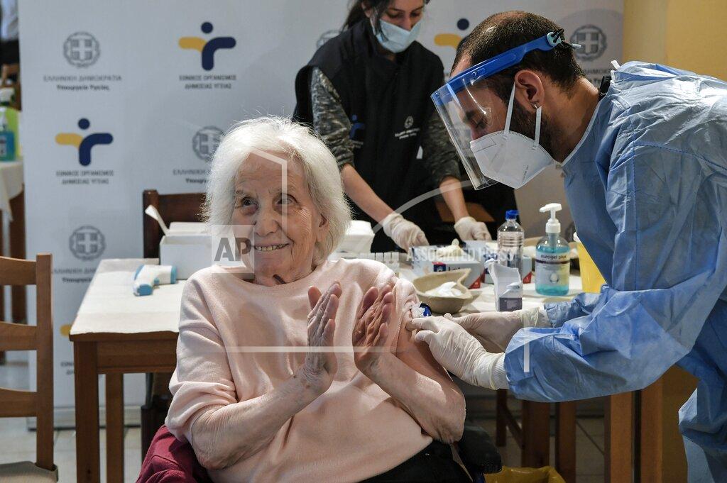 Lousia Gouliamaki An elderly woman applauds during a vaccination at a nursing house in Athens, Monday, Jan. 4, 2021. Vaccinations were expanded from 9 to 50 hospitals nationwide on Monday. (Louisa Gouliamaki/Pool via AP)