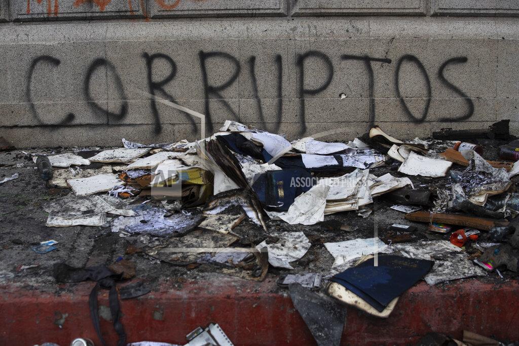 Moises Castillo Debris lays in front of graffiti that reads in Spanish "Corrupt," outside of the Congress building that was damaged during protests in Guatemala City, Sunday, Nov. 22, 2020. Protesters broke into the building and set it partially on fire amid growing demonstrations against President Alejandro Giammattei and the legislature for approving a controversial budget that cut educational and health spending. (AP Photo/Moises Castillo)
