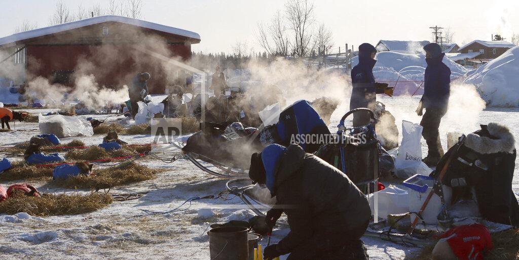 Zachariah Hughes Mushers handle their dog care on a cold morning in the McGrath, Alaska, checkpoint during the Iditarod Trail Sled Dog Race on Saturday, March 13, 2021. (Zachariah Hughes/Anchorage Daily News via AP, Pool)
