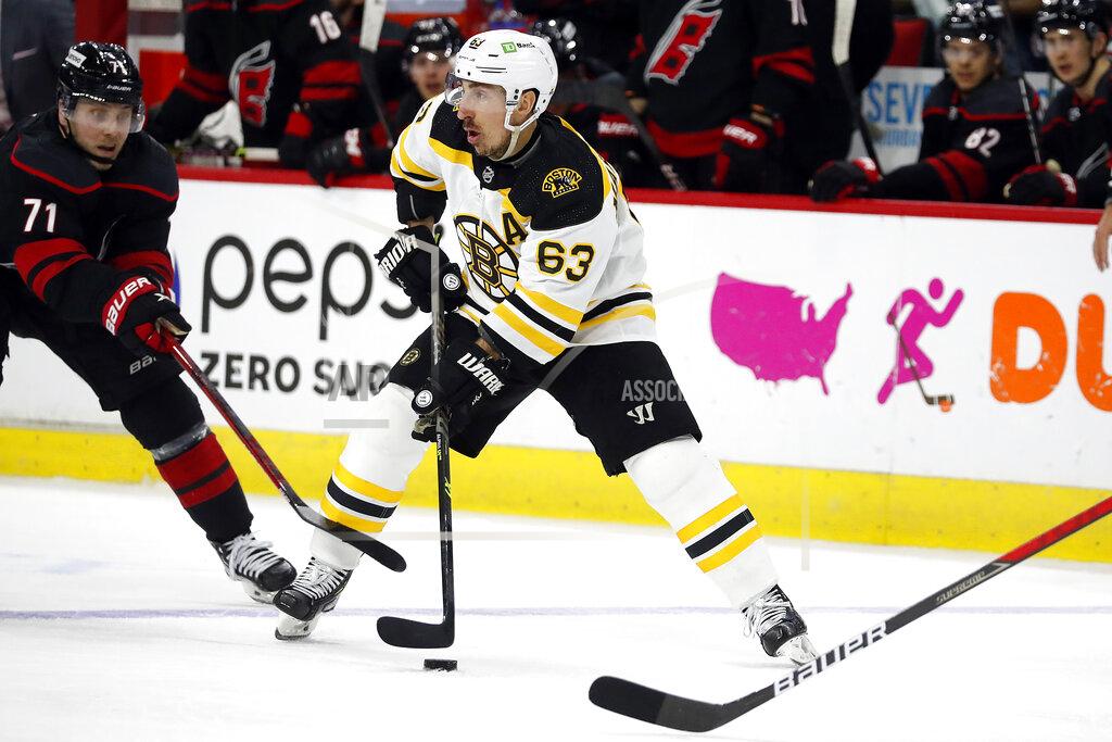 Karl B Deblaker Boston Bruins' Brad Marchand (63) tries to move the puck around Carolina Hurricanes' Jesper Fast (71) during the third period of Game 7 of an NHL hockey Stanley Cup first-round playoff series in Raleigh, N.C., Saturday, May 14, 2022. (AP Photo/Karl B DeBlaker)