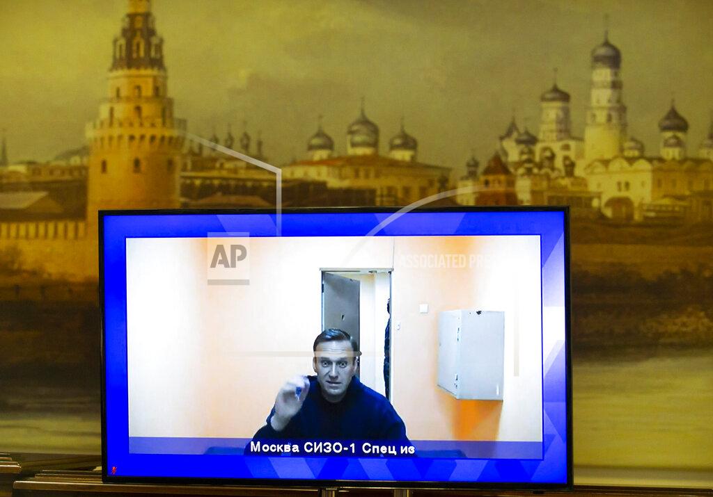Alexander Zemlianichenko Russian opposition leader Alexei Navalny appears on a TV screen during a live session with the court during a hearing of his appeal in a court in Moscow, Russia, Thursday, Jan. 28, 2021, with the wall with the image of the Moscow Kremlin in the background. Navalny was jailed soon after arriving to Moscow after authorities accused him of violating of the terms of his 2014 fraud conviction. A court on Thursday is to hear an appeal on the ruling to remand him into custody. Next week, another court will decide whether to send him to prison for several years for the alleged violations. (AP Photo/Alexander Zemlianichenko)