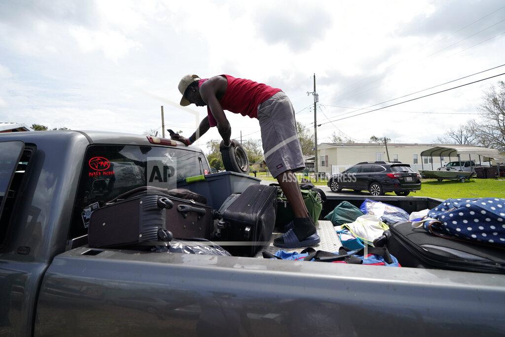 Gerald Herbert Bernie Murray rearranges luggage in Lake Charles, La., as he returns with eight family members in one truck, after evacuating from Hurricane Laura, Sunday, Aug. 30, 2020. (AP Photo/Gerald Herbert)