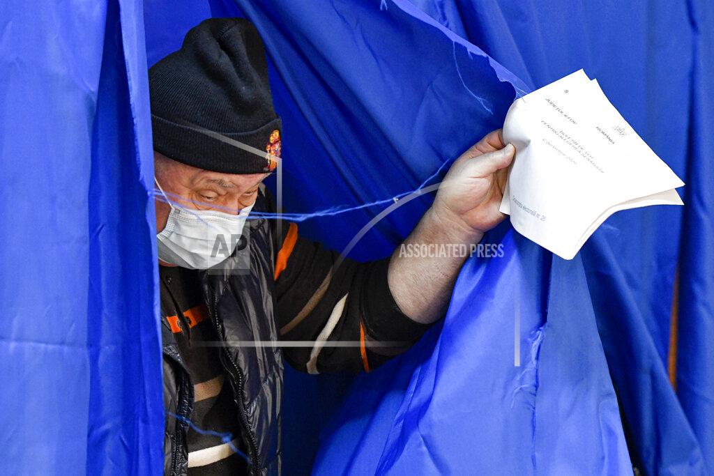 Andreea Alexandru A man wearing a mask for protection against the COVID-19 infection exits a voting cabin in the village of Branesti, Romania, Sunday, Dec. 6, 2020. Voting started in Romania's legislative election expected to restore some measure of stability after five years of political and social turbulence with more than 18 million Romanians registered to vote for a new legislative body. (AP Photo/Andreea Alexandru)