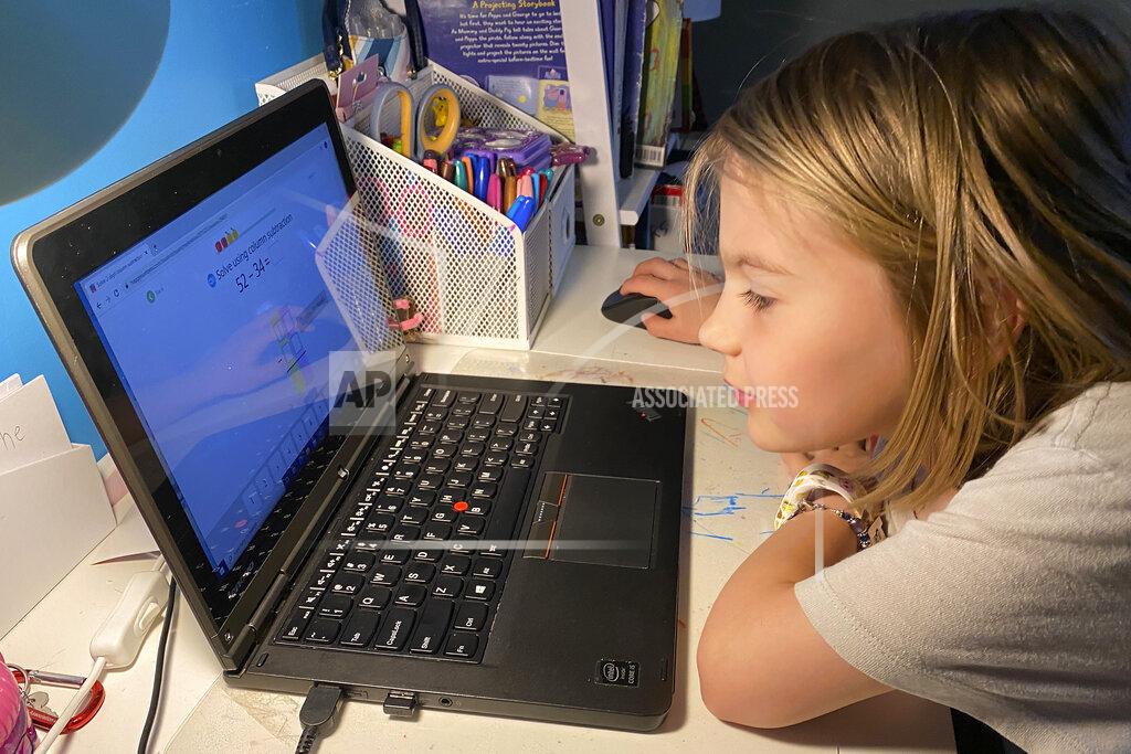 This April 9, 2020, photo released by Kara Illig shows her daughter, Ainslie Illig, 8, on her computer in Ebensburg, Pa. The frustration of parents is mounting as more families across the U.S. enter their second or even third week of total distance learning, and some say it will be their last. (Kara Illig via AP)