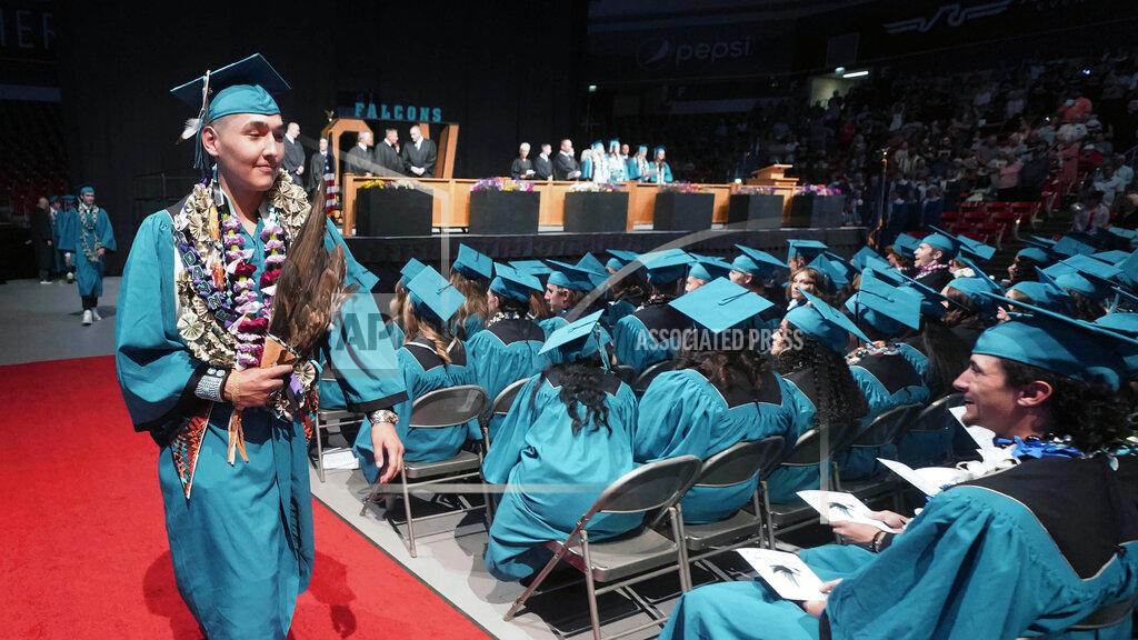 Rick Bowmer Dayne Hudson, member of the Paiute Indian Tribe of Utah, walks with his eagle feather fan during the Canyon View High School graduation Wednesday, May 25, 2022, in Cedar City, Utah. Hudson said it was important to wear eagle feathers and a beaded cap to represent his family and honor those who were stopped from doing so under the old rule. (AP Photo/Rick Bowmer)