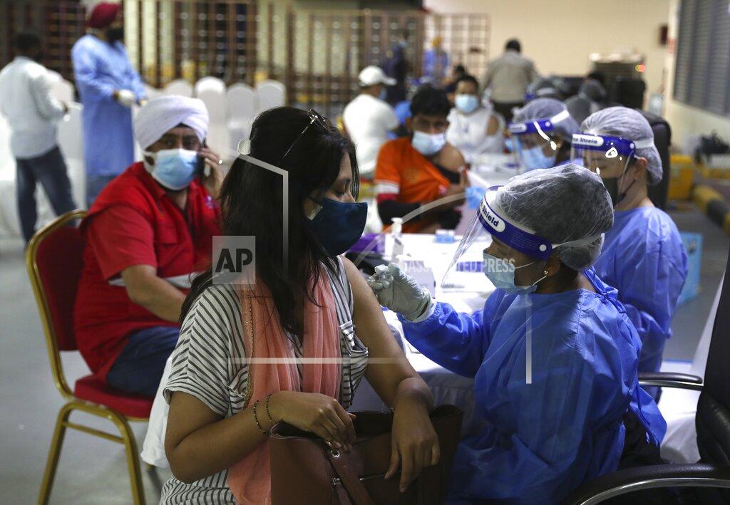 A woman receives a Sinopharm COVID-19 vaccine from a medical staffer at the Guru Nanak Darbar Sikh Temple, in Dubai, United Arab Emirates, Monday, Feb. 8, 2021. With the coronavirus pandemic surging to new heights in the UAE, the Sikhs of Dubai have traded their traditional fare of free meals for free COVID-19 vaccines. The city's Sikh temple is administering 5,000 shots to those who may otherwise struggle to be vaccinated. (AP Photo/Kamran Jebreili)