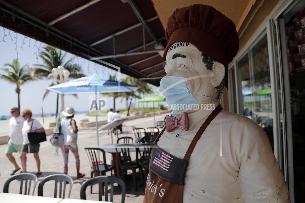 CORRECTS TO BROADWALK, INSTEAD OF BOARDWALK A statue of a chef at Florio's of Little Italy restaurant wears a protective face mask on the Hollywood Beach Broadwalk during the new coronavirus pandemic, Thursday, July 2, 2020, in Hollywood, Fla. In hard-hit South Florida, beaches from Palm Beach to Key West will be shut down for the Fourth of July holiday weekend. Restaurants and businesses along the Boardwalk will remain open. (AP Photo/Lynne Sladky)