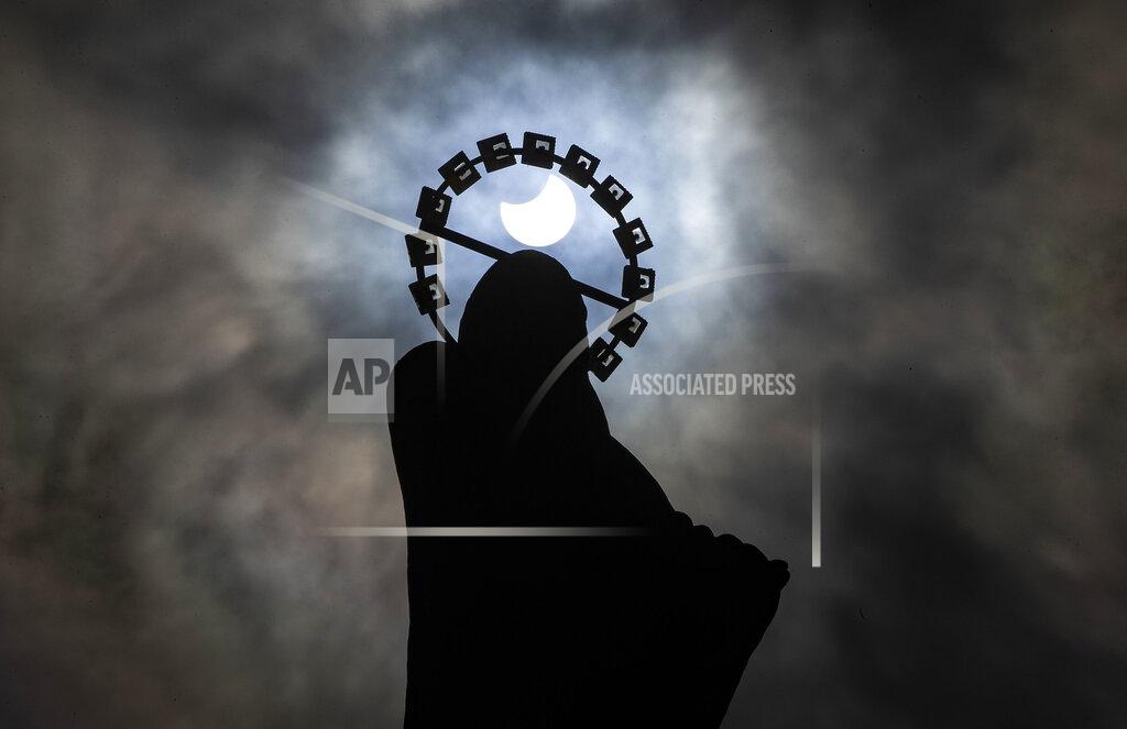 Brian Lawless A statue of Our Lady, Star Of The Sea on Bull Wall in Dublin, is silhouetted against the sky during a partial solar eclipse, Thursday, June 10, 2021. (Brian Lawless/PA via AP)