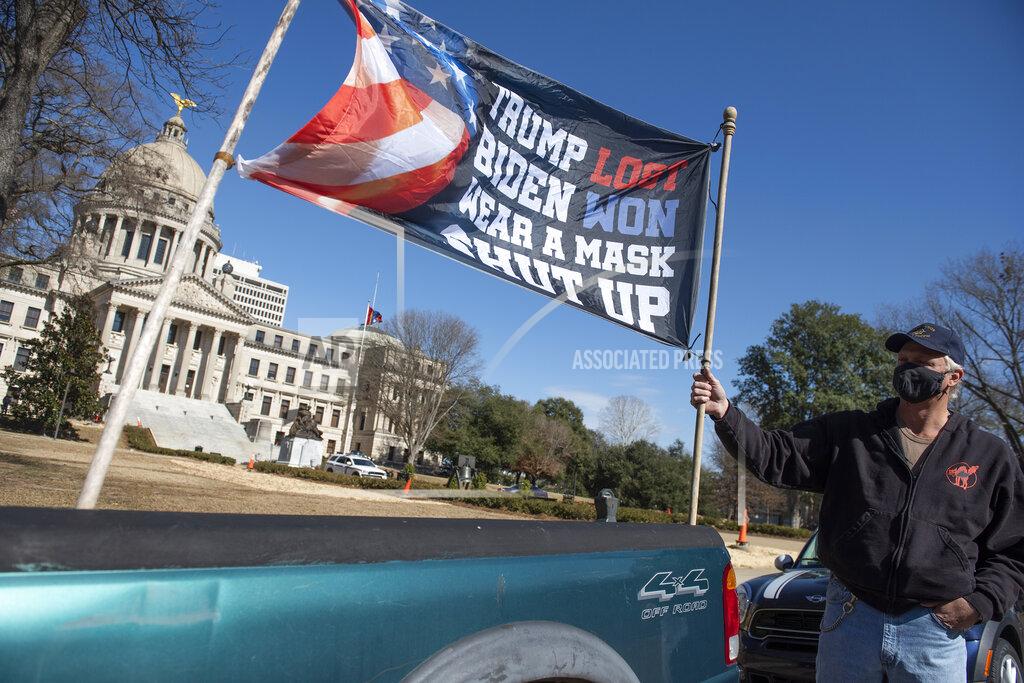 Barbara Gauntt Dale Gibson, of Jackson, Miss., shows off the banner he planned to hold as a counter-protester if a pro-Trump rally materialized Sunday, Jan. 17, 2021. "But they done ruined my whole Sunday. Now I have to go and get drunk," Gibson said. Visibly enhanced security surrounded the Mississippi State Capitol in Jackson, Miss., after FBI warned armed protests had been planned at all 50 state capitols leading up to the inauguration of President-elect Joe Biden. (Barbara Gauntt/The Clarion-Ledger via AP)