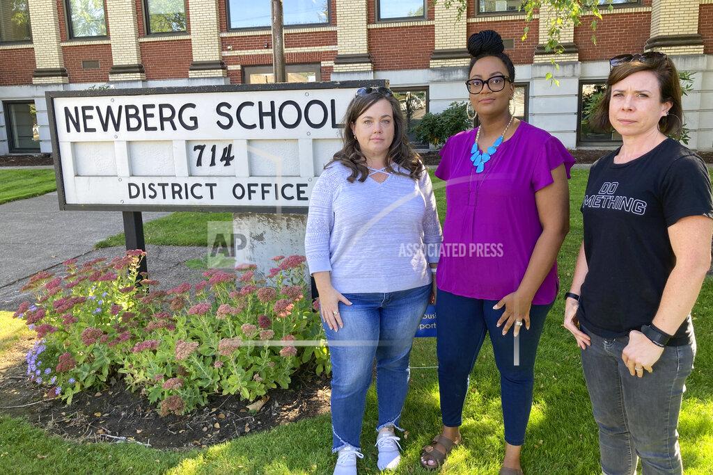Andrew Selsky From left, Beth Woolsey, Tai Haden-Moore and AJ Schwanz , who are members of a group called Newberg Equity in Education which is advocating for inclusion and equity in schools, stand in front of a school district office in Newberg, Ore., on Tuesday, Sept. 21, 2021. The Newberg School Board has banned educators from displaying Black Lives Matter and gay pride symbols, prompting a torrent of recriminations and threats to boycott the town and its businesses. (AP Photo/Andrew Selsky)