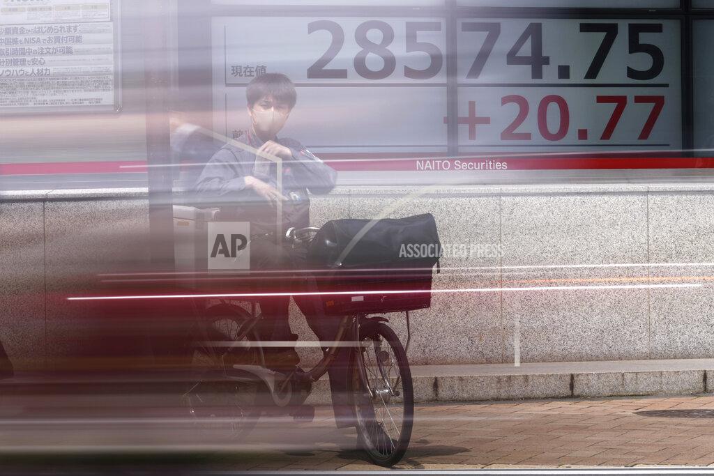 Eugene Hoshiko A man wearing a protective mask rides a bicycle in front of an electronic stock board showing Japan's Nikkei 225 index at a securities firm Wednesday, May 26, 2021, in Tokyo. Asian stock markets rose Wednesday as inflation fears eased and investors looked ahead to U.S. data that are expected to show economic growth accelerating. (AP Photo/Eugene Hoshiko)