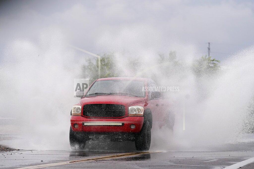 Ross D. Franklin A vehicle sprays water in the air while driving through standing water as heavy rains caused flooding, Friday, July 23, 2021, in Phoenix. (AP Photo/Ross D. Franklin)
