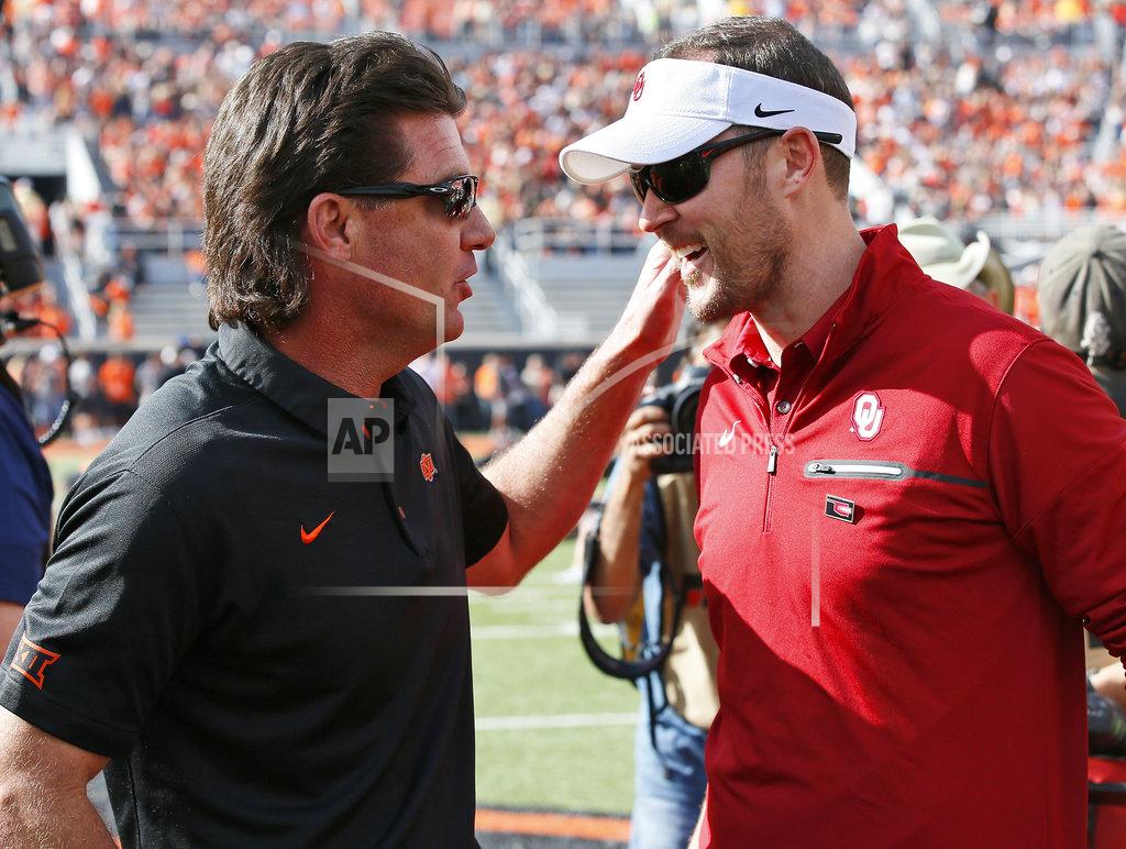 FILE - In this Saturday, Nov. 4, 2017, file photo, Oklahoma State head coach Mike Gundy, left, talks with Oklahoma head coach Lincoln Riley, right, before their NCAA college football game in Stillwater, Okla. While Oklahoma State has been erratic this season, and has been dominated in the rivalry series, the Cowboys have made it to overtime in two of their last three road games against Oklahoma. they won there in 2014, after an OT loss in 2012. (AP Photo/Sue Ogrocki, File)