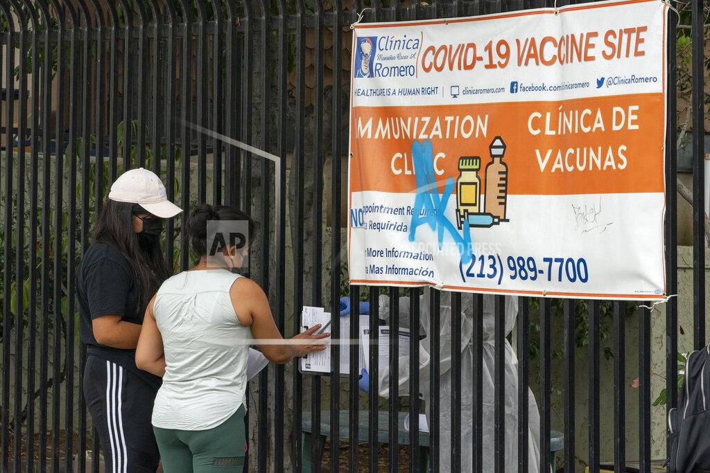 Damian Dovarganes Immigrants fill out forms before getting vaccinated at the Clínica Monseñor Oscar A. Romero in the Pico-Union district of Los Angeles, Monday, July 26, 2021. The clinic is a COVID-19 vaccine site. California said it will require proof of vaccination or weekly testing for all state workers and millions of public- and private-sector health care employees starting in August. (AP Photo/Damian Dovarganes)