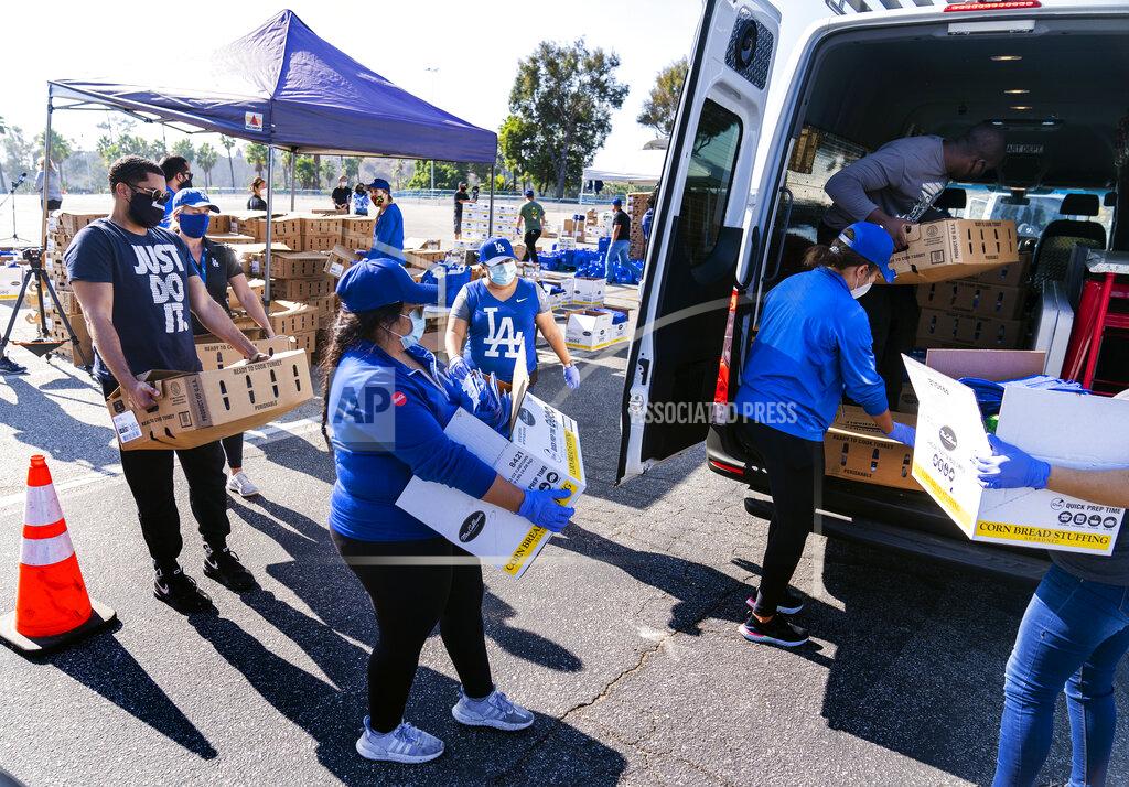 Volunteers help distribute some 1,500 Thanksgiving meals, including an assortment of dinner fixings at a drive-thru to not-for-profit community organizations at Dodger Stadium parking lot in Los Angeles Thursday, Nov. 19, 2020. Los Angeles Dodgers, the Los Angeles Dodgers Foundation (LADF), and team partner Smart & Final host the 16th annual Community Thanksgiving Turkey Giveaway. (AP Photo/Damian Dovarganes)