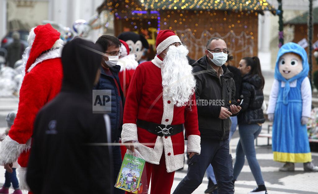 Boris Grdanoski In this picture taken on Tuesday, Dec. 29, 2020, men dressed as Santa Claus hang around, as people wearing face masks walk through downtown Skopje, North Macedonia. When thousands of people across the European Union simultaneously began rolling up their sleeves last month to get a coronavirus vaccination shot, one corner of the continent was left behind, feeling isolated and abandoned: the Balkans. (AP Photo/Boris Grdanoski)