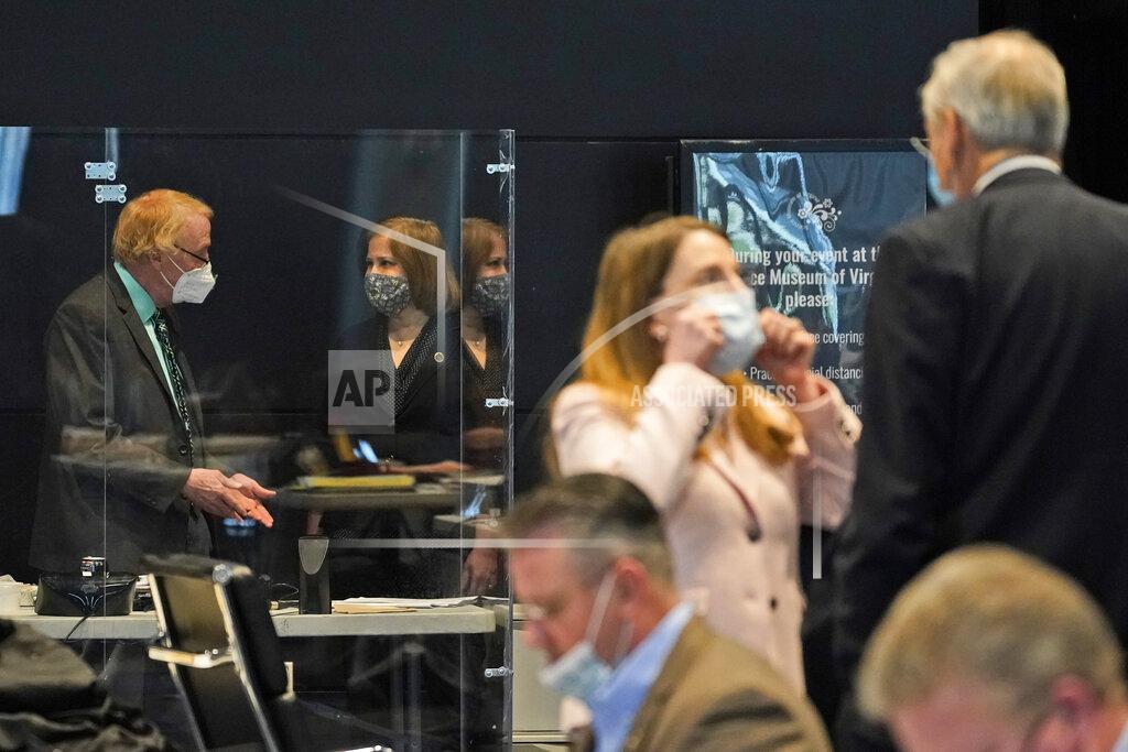 Steve Helber Virginia State Sen. George Barker, D-Fairfax, left, talks with Sen. Ghazala Hashmi, D-Chesterfield, second from left, during the Virginia Senate session at the Science Museum in Richmond, Va., Tuesday, Feb. 16, 2021. Barker is behind a protective enclosure due to health issues. (AP Photo/Steve Helber)