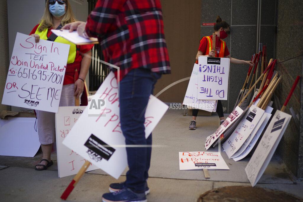 Jeff Wheeler Picketers sign in and pick up signs from Tara Fugate, right, a staffer with the Minnesota Nurses Association, Wednesday, May 20, 2020, in St. Paul, Minn., during an informational picket Along Smith Avenue outside United Hospital. Nurse members are asking for a say in worker protections, increased PPE resources with higher safety standards and an end to retaliation against workers who have tried to protect themselves from the COVID-19 virus. After picketing, they marched to the State Capitol to hear speakers. (Jeff Wheeler/Star Tribune via AP)