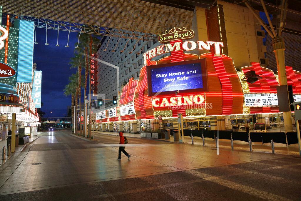 John Locher FILE - In this March 21, 2020, file photo, a man walks along a usually busy Fremont Street after casinos were ordered to shut down due to the coronavirus outbreak in Las Vegas. A U.S. casino company with 29 properties in 10 states is laying off thousands of employees, citing a slow restart to business following closures due to the coronavirus pandemic. Las Vegas-based Boyd Gaming Corp., said in a statement Monday, July 13, 2020, that an unspecified number of furloughed employees will not return. As many as 2,500 company workers in Nevada could be affected. The publicly-traded company had about 10,000 employees in Nevada and another 14,300 nationally, according to its last annual report. It also has properties in Illinois, Indiana, Iowa, Kansas, Louisiana, Mississippi, Missouri, Ohio, and Pennsylvania. (AP Photo/John Locher, File)