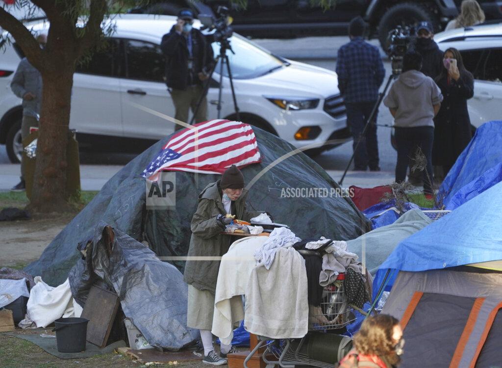 Damian Dovarganes FILE - In this March 24, 2021, file photo a woman eats at her tent at the Echo Park homeless encampment at Echo Park Lake in Los Angeles. California Gov. Gavin Newsom announced a $12 billion plan Tuesday, May 11 to confront the state's homelessness crisis. (AP Photo/Damian Dovarganes, File)
