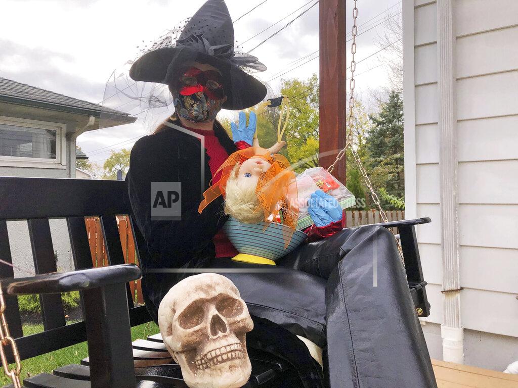 Julie Carr Smyth Julie Schirmer sits at her home in Columbus, Ohio, on Saturday, Oct. 24, 2020, with the decorated slingshot she’ll use to deliver bagged, sanitized candy bars on Halloween. The favorite American festivity of Halloween trick-or-treating is being tested by the pandemic, and people are rising to the challenge in creative ways that are both safe and fun. (AP Photo/Julie Carr Smyth)