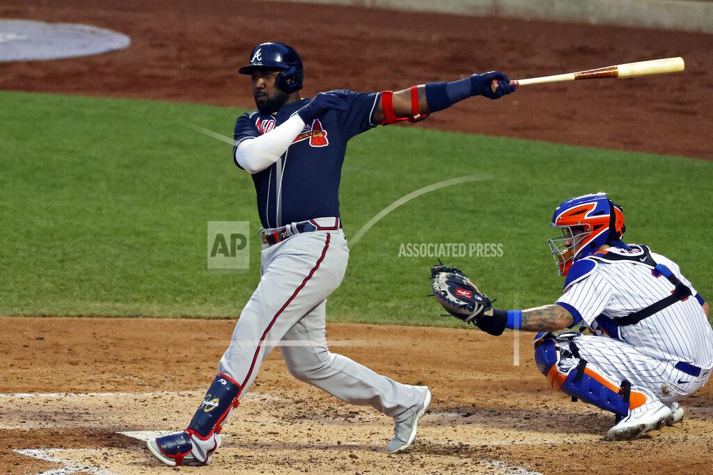 Adam Hunger Atlanta Braves' Marcell Ozuna follows through on an RBI double in front of New York Mets catcher Tomás Nido during the third inning of a baseball game Sunday, July 26, 2020, in New York. (AP Photo/Adam Hunger)