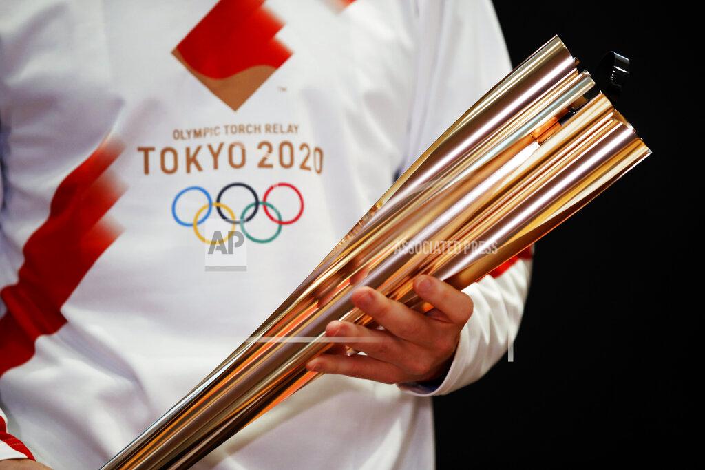 FILE - In this Feb. 24, 2020, file photo, Greek singer Sakis Rouvas wears the uniform of the torch relay runners in Athens, Greece, as he holds the torch of the 2020 Tokyo Olympic Games during a presentation of the torch relay within in Greece. A governor in a western Japanese prefecture is talking about canceling the torch relay events in his area for the Tokyo Olympics, Kyodo News reported Wednesday, Feb. 17, 2021. (AP Photo/Thanassis Stavrakis)