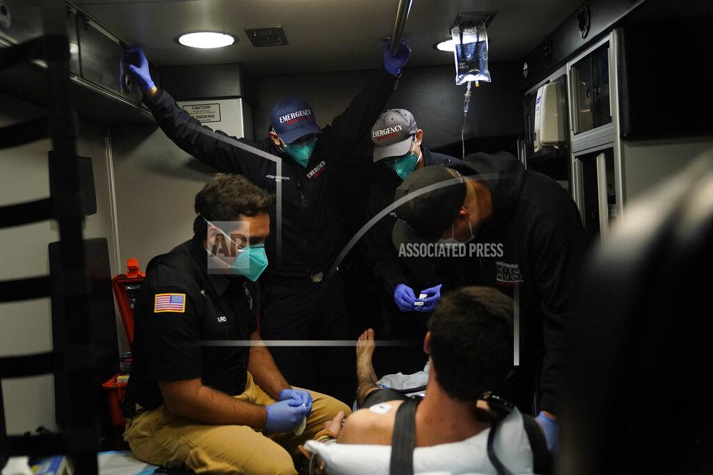 Jae C. Hong Emergency medical workers Trenton Amaro, from left, Joshua Hammond, Thomas Hoang and Charles Navarro are crammed in an ambulance as they treat a patient in Placentia, Calif., Friday, Jan. 8, 2021. EMTs and paramedics have always dealt with life and death — they make split-second decisions about patient care, which hospital to race to, the best and fastest way to save someone — and now they're just a breath away from becoming the patient themselves.(AP Photo/Jae C. Hong)