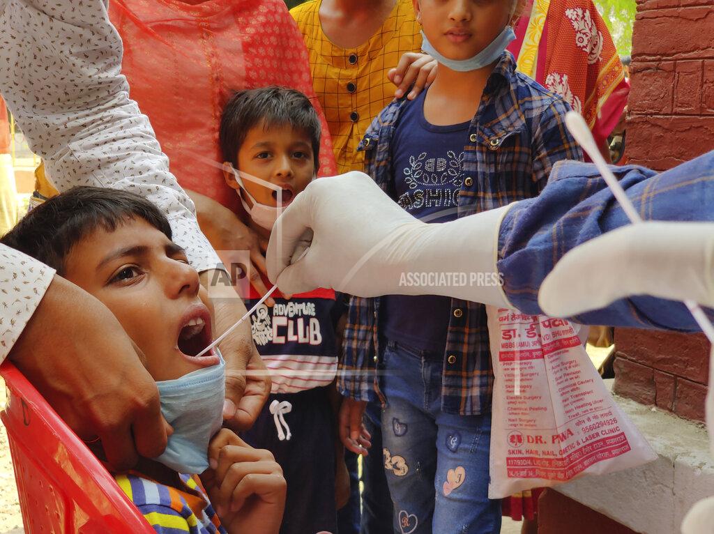 Rajesh Kumar Singh A health worker takes swab sample of children to test for COVID-19 in Prayagraj, India, Thursday, April 8, 2021. Nations around the world set new records Thursday for COVID-19 deaths and new coronavirus infections, and the disease surged even in some countries that have kept the virus in check. Indian Prime Minister Narendra Modi urged people to get vaccinated, writing in a tweet: “Vaccination is among the few ways we have to defeat the virus. If you are eligible for the vaccine, get your shot soon.” (AP Photo/Rajesh Kumar Singh)