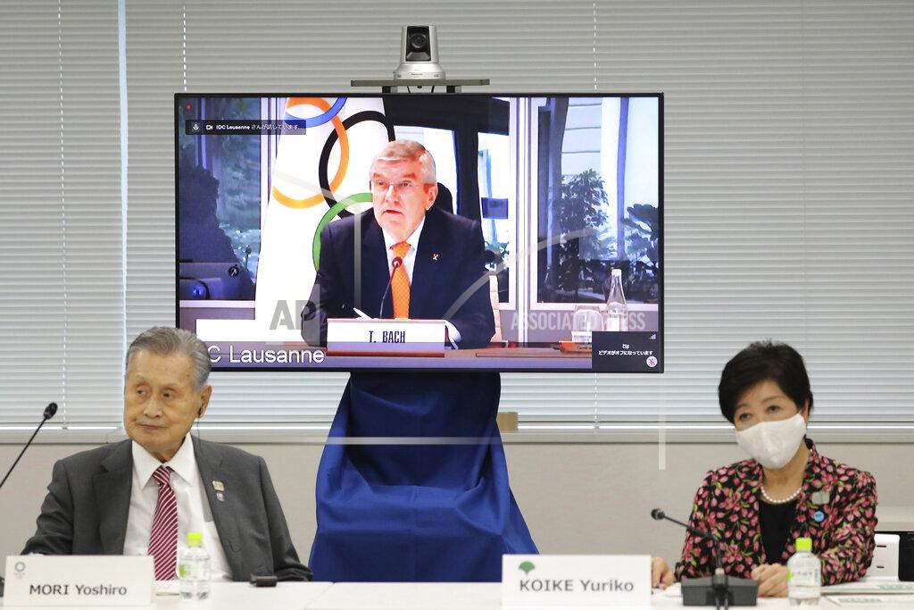 In this Sept. 24, 2020, file photo, IOC President Thomas Bach, on the screen, speaks remotely with Tokyo 2020 Organizing Committee President Yoshiro Mori, left, and Tokyo Gov. Yuriko Koike, right, during an on-line meeting focused on how to pull off the delayed Tokyo Games, in Tokyo. The IOC and local organizers are trying to “simplify” next year's postponed Tokyo Olympics, promising to save money in what one study says is already the most expensive Summer Olympics on record. (Du Xiaoyi/Pool Photo via AP)