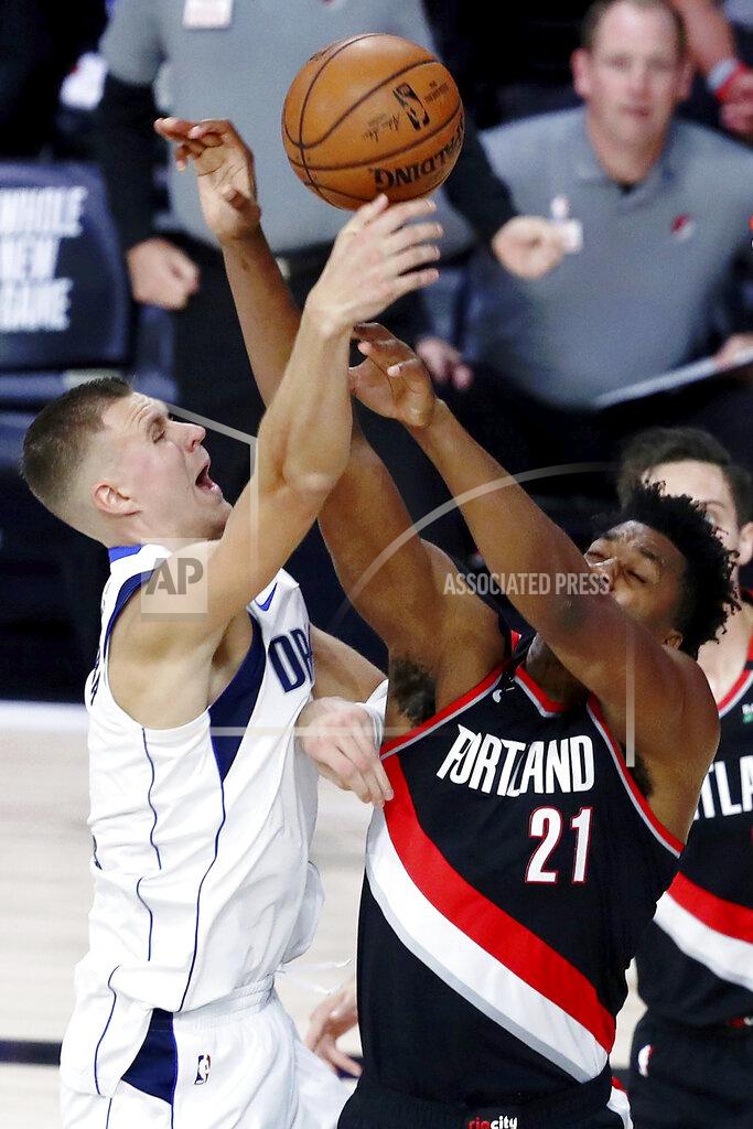 Kim Klement Portland Trail Blazers center Hassan Whiteside (21) and Dallas Mavericks forward Kristaps Porzingis (6) during the first half of an NBA basketball game Tuesday, Aug. 11, 2020, in Lake Buena Vista, Fla. (Kim Klement/Pool Photo via AP)