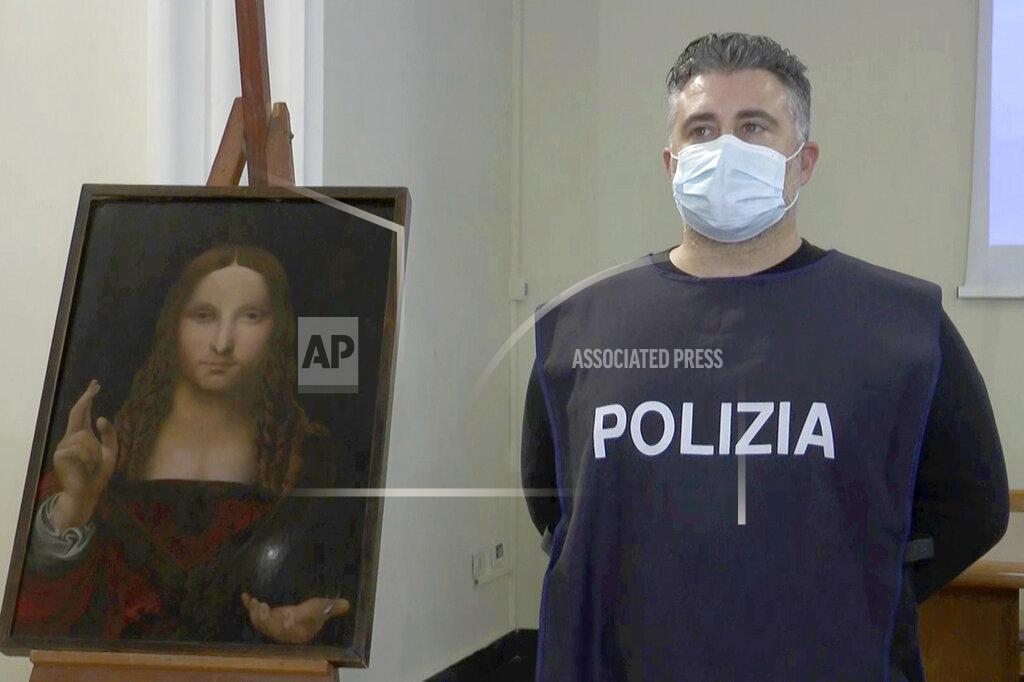 Sicomunicazione In this image taken from a video, a police officer poses by a copy of the “Salvator Mundi” (Savior of the World) by Leonardo da Vinci, in Naples, Italy, Wednesday, Jan. 20, 2021. Italian police have recovered a copy of Leonardo da Vinci’s 16th century “Salvator Mundi” painting of Jesus Christ that was stolen from a Naples church without the priests even realizing it was gone. The discovery was made over the weekend when Naples police working on a bigger operation found the painting hidden in an apartment. Police chief Alfredo Fabbrocini said the owner offered a “less than credible” explanation that he had “casually” bought it at a small market. (AP Photo/Sicomunicazione)