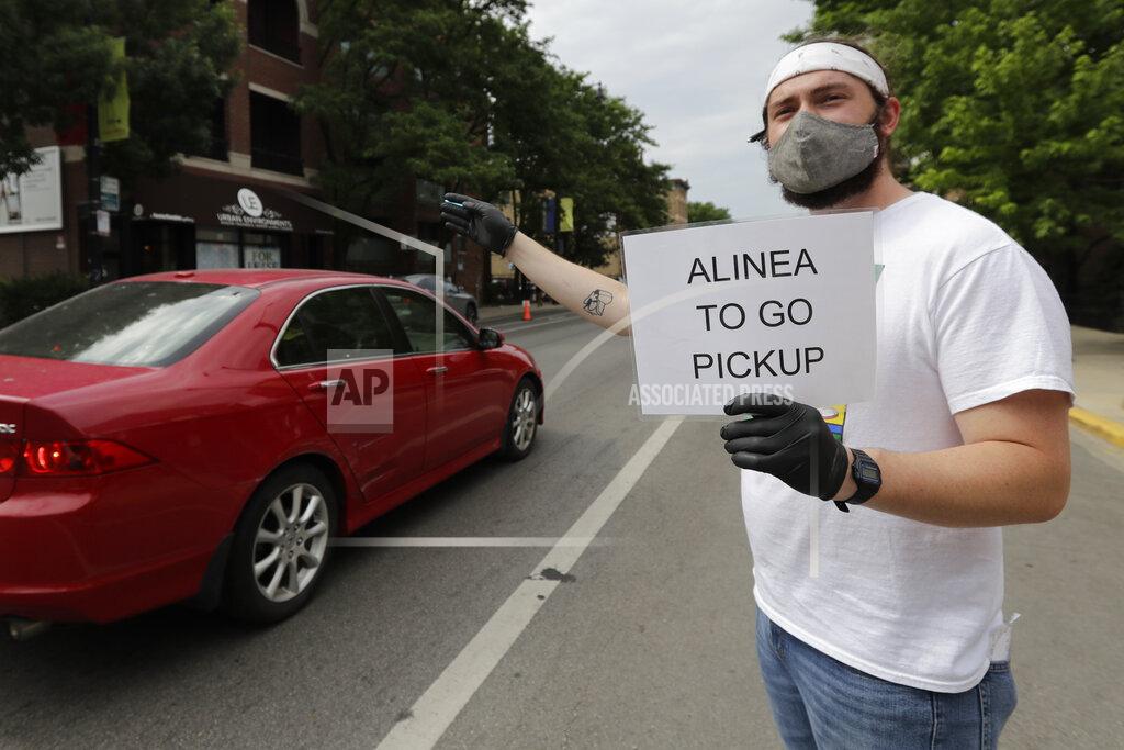 Nam Y. Huh Cal Barnett, a staffer from Alinea restaurant, holds a sign for carryout customers in Chicago, Saturday, June 20, 2020. Due to the coronavirus Alinea shifted to carryout on March 17. Since then, it has served 82,000 meals, said Nick Kokonas, the restaurant's co-owner. (AP Photo/Nam Y. Huh)
