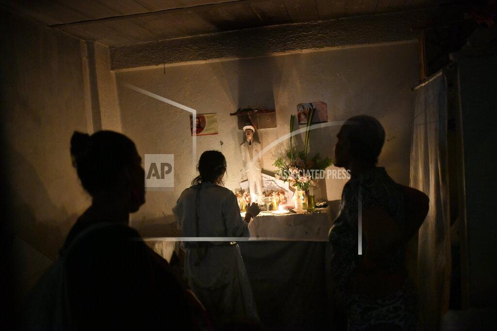Matias Delacroix People stand before an altar featuring a statue of the late, Venezuelan Dr. Jose Gregorio Hernandez on the day of his beatification ceremony by the Catholic church, inside a residence in Caracas, Venezuela, Friday, April 30, 2021. Known as the "doctor of the poor," Hernandez is being beatified, a step towards sainthood. (AP Photo/Matias Delacroix)