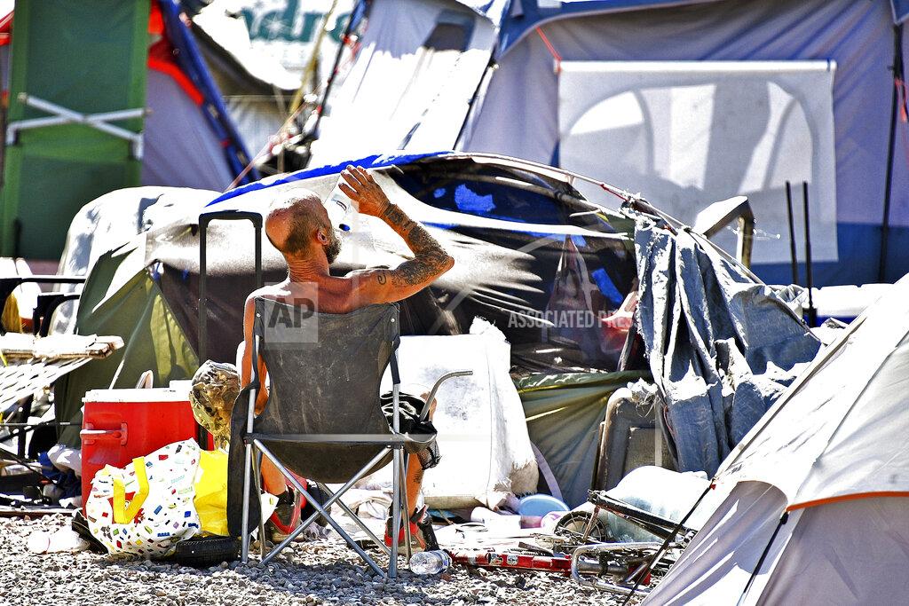 Steve Carr A homeless man sits by his belongings at the Lots, a county-run outdoor encampment in downtown Phoenix, on June 24, 2020. Homeless people are among the most vulnerable populations in the COVID-19 pandemic, yet they're largely invisible victims. Very little is known about how they're faring. The U.S. Department of Housing and Urban Development, which oversees homeless programs, has not required its national network of providers to gather infection or death data, even though homeless people, unlike other high-risk groups such as nursing home residents, interact more with the public. (Steve Carr/Human Services Campus and the Howard Center For Investigative Journalism via AP)