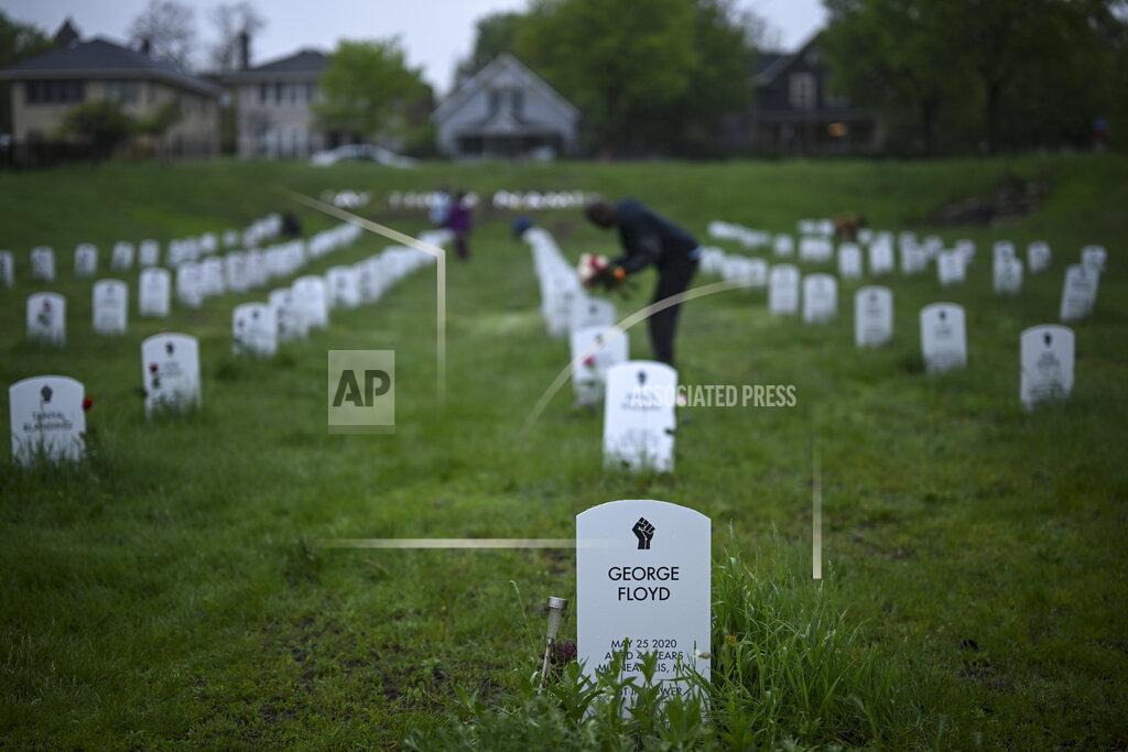 Aaron Lavinsky Community members lay flowers down near gravestone markers at the 'Say Their Names' cemetery Wednesday, May 25, 2022, in Minneapolis. The intersection where George Floyd died at the hands of Minneapolis police officers was renamed in his honor Wednesday, among a series of events to remember a man whose killing forced America to confront racial injustice. (Aaron Lavinsky/Star Tribune via AP)